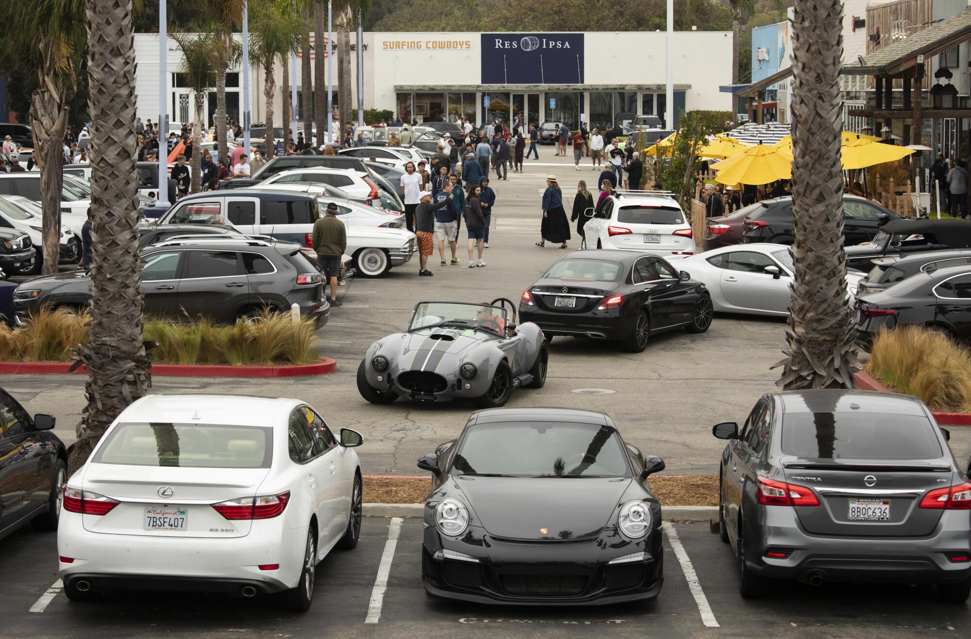 The parking lot at Malibu Village Shopping Mall is filled to capacity with car enthusiasts and customers vying for spots.