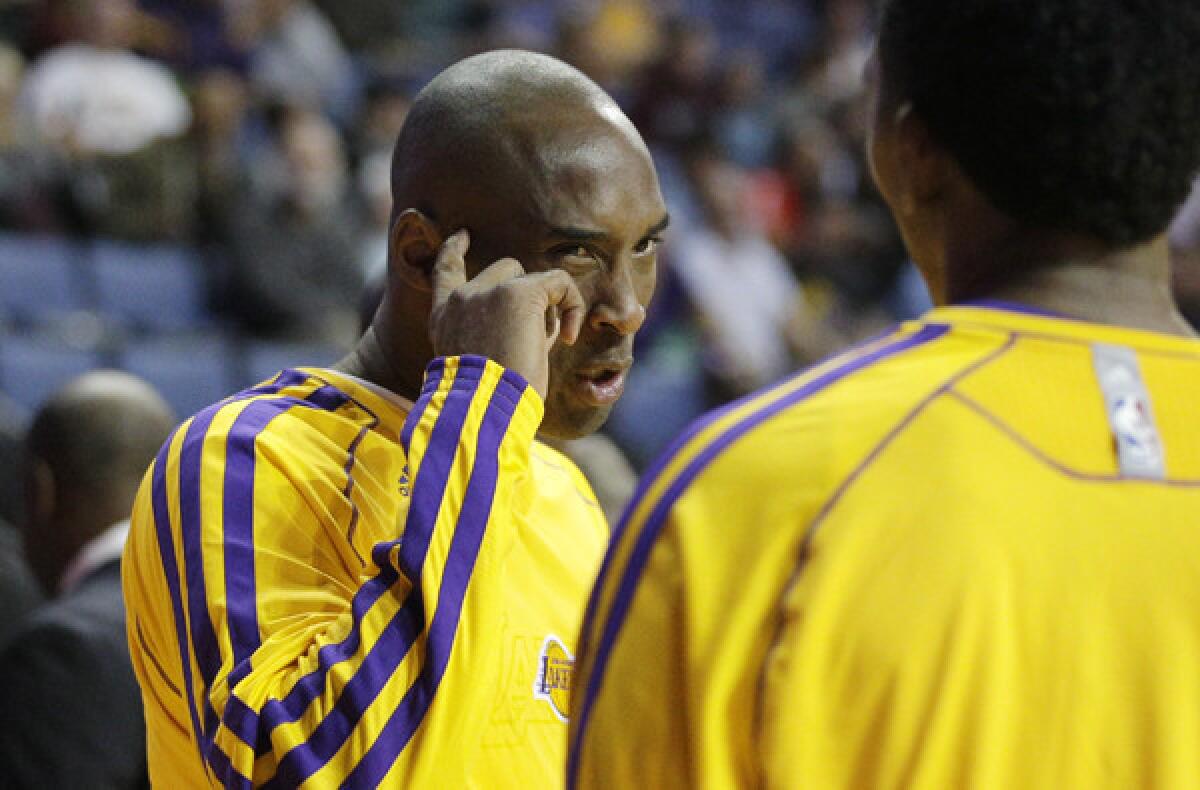 Lakers guard Kobe Bryant talks to teammate Nick Young before a preseason game against the Denver Nuggets on Tuesday. Bryant has not played as he continued to rehabilitate his surgically repaired left Achilles' tendon.