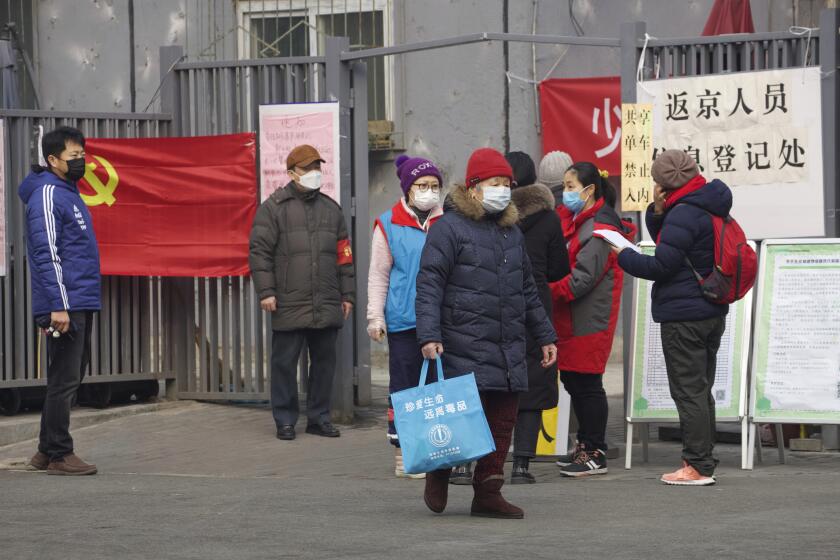 Residentes esperan para entrar a un punto de control que dice "punto de registro para personas que regresan a Beijing" en Beijing, China, el jueves 13 de febrero de 2020. (AP Foto/Ng Han Guan)