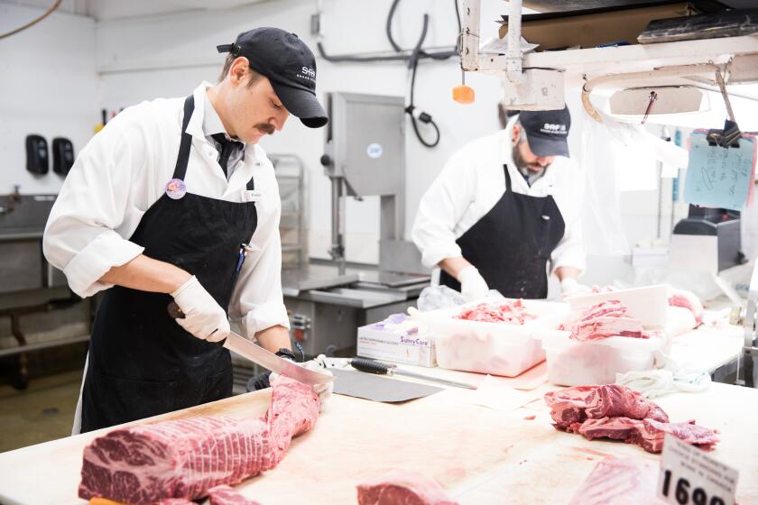 Tristan Gallo, left, and Greg Stoffel cut meat at Corti Bros. grocery store in Sacramento, California, September 17, 2019.