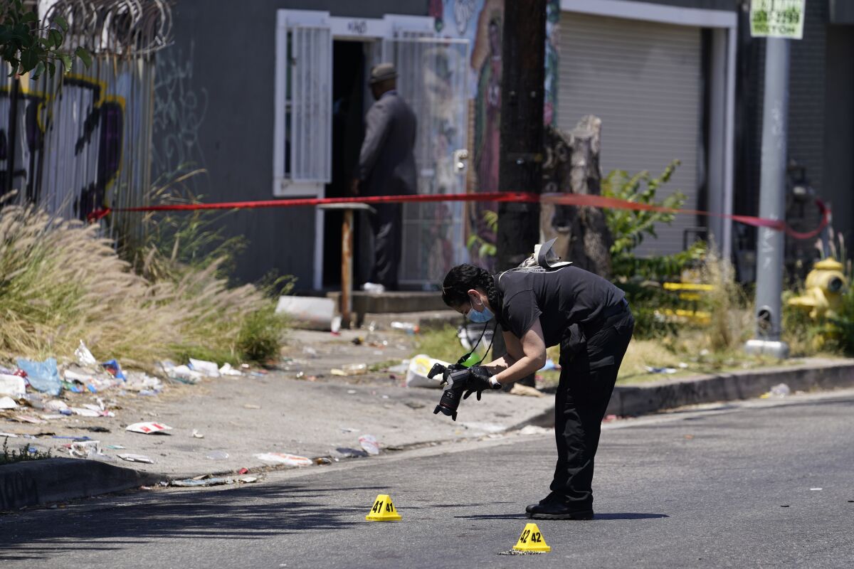 A Los Angeles Police field forensic photographer documents evidence after a shooting at a warehouse party in Los Angeles, Sunday, June 12, 2022. (AP Photo/Damian Dovarganes)