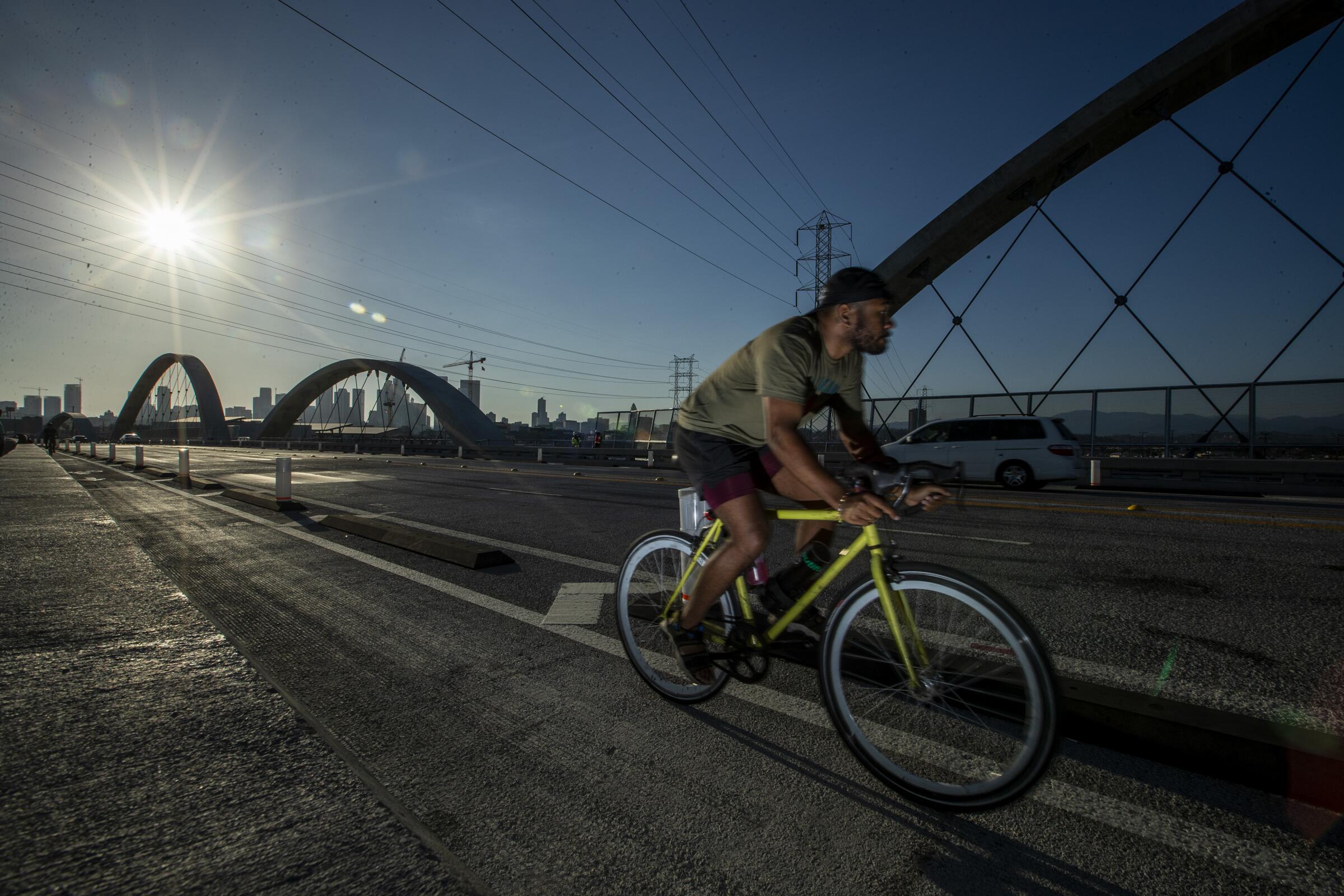 A cyclist riding a yellow bicycle across a bridge using the bike lane