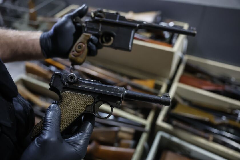 A German Luger P08 from World War II is held by a gunsmith in front of boxes of weapons is seen in a box of weapons in Strasbourg, eastern France, Wednesday, Nov. 30, 2022. France has launched a nationwide drive to collect millions of old firearms, remnants of the two World Wars or long-abandoned hunting excursions. French Interior Ministry officials suspect French families keep many unregistered weapons tucked away in attics and storerooms as heirlooms in the country that was once the scene of many of the last century's fiercest battles. (AP Photo/Jean-Francois Badias)