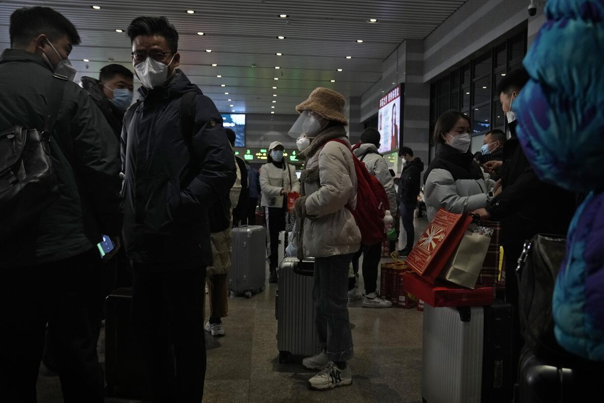 Travelers in face masks prepare to catch their trains at the West Railway Station in Beijing.