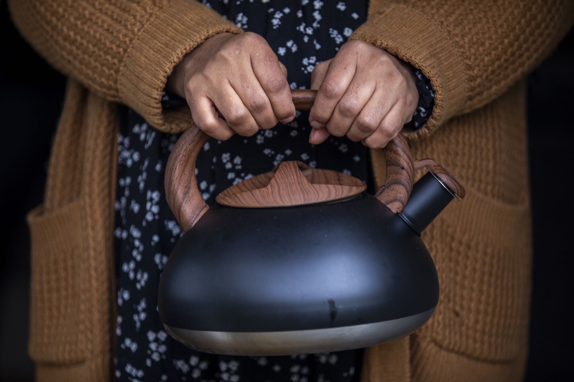 A woman holds a tea kettle.