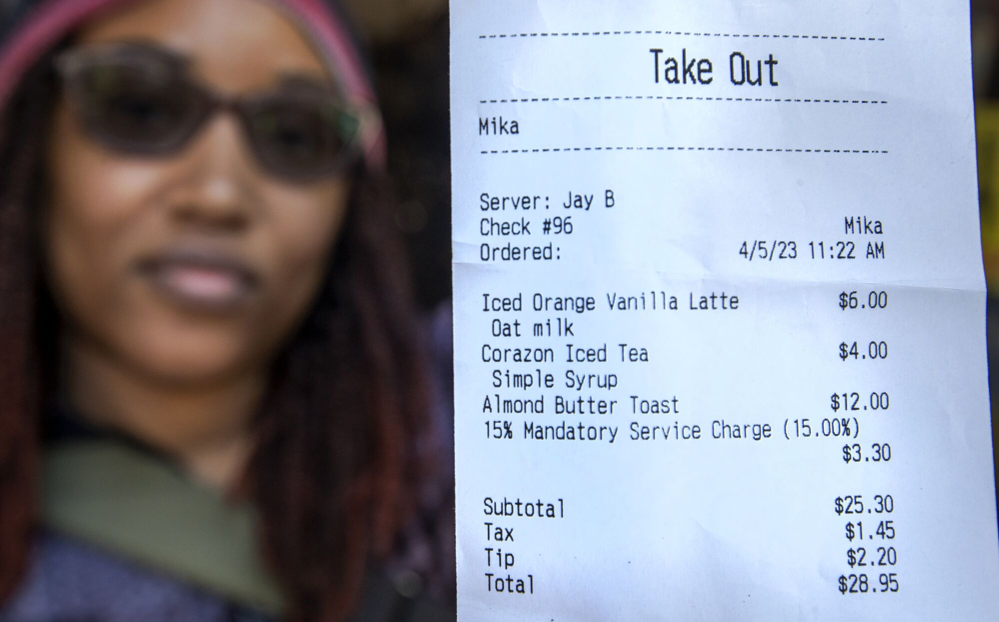 A woman shows her receipt that included a mandatory 15% service charge and a tip she left in addition to that.