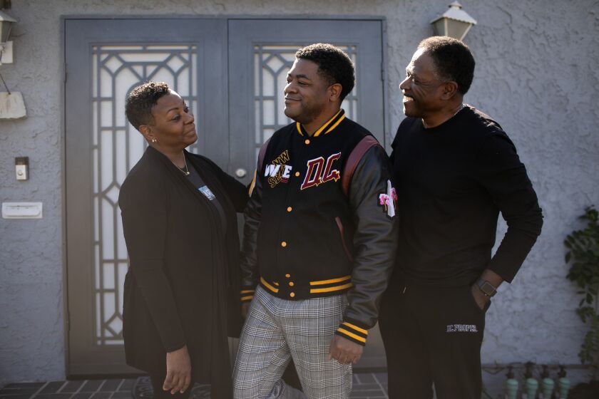 COMPTON, CA - FEBRUARY 20: David Colbert, Jr., executive director and founder of Compton Art Walk, Inc. and Gallery 90220 along with his mother Yolandra and father David Colbert, Sr. stand outside of his parent home on Monday, Feb. 20, 2023 in Compton, CA. (Jason Armond / Los Angeles Times)