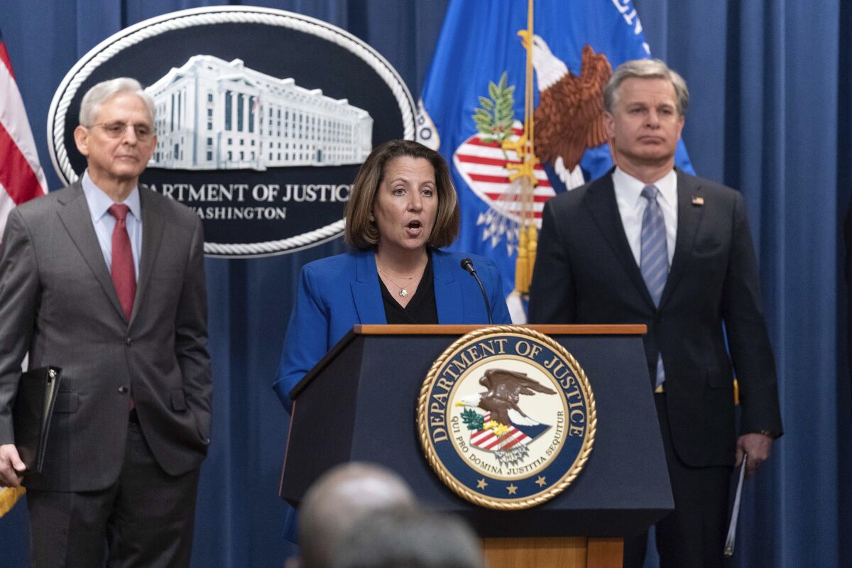 Three U.S. officials stand on a podium at a news conference.
