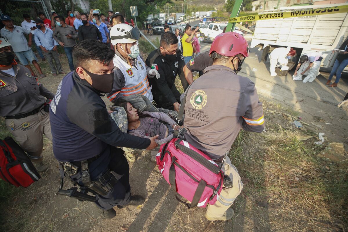 An injured migrant woman is moved by rescue personnel from the site of an accident near Tuxtla Gutierrez, Chiapas state, Mexico, Dec. 9, 2021. Mexican authorities say at least 49 people were killed and dozens more injured when the truck carrying the migrants rolled over on the highway in southern Mexico. (AP Photo)