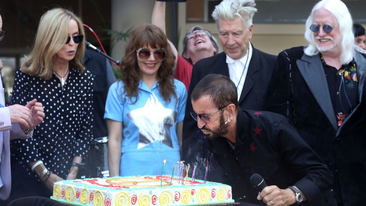 Ringo Starr blows out the candles on a cake during his annual "Peace and Love" birthday celebration.