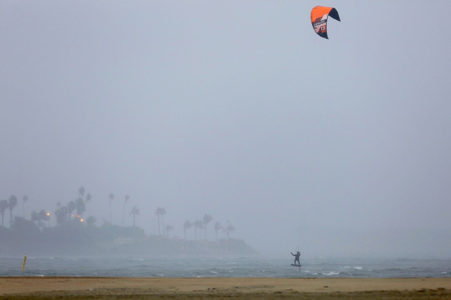 A kite surfer in Long Beach makes use of the wind during the rainy weather brought by the first big storm of the new year.