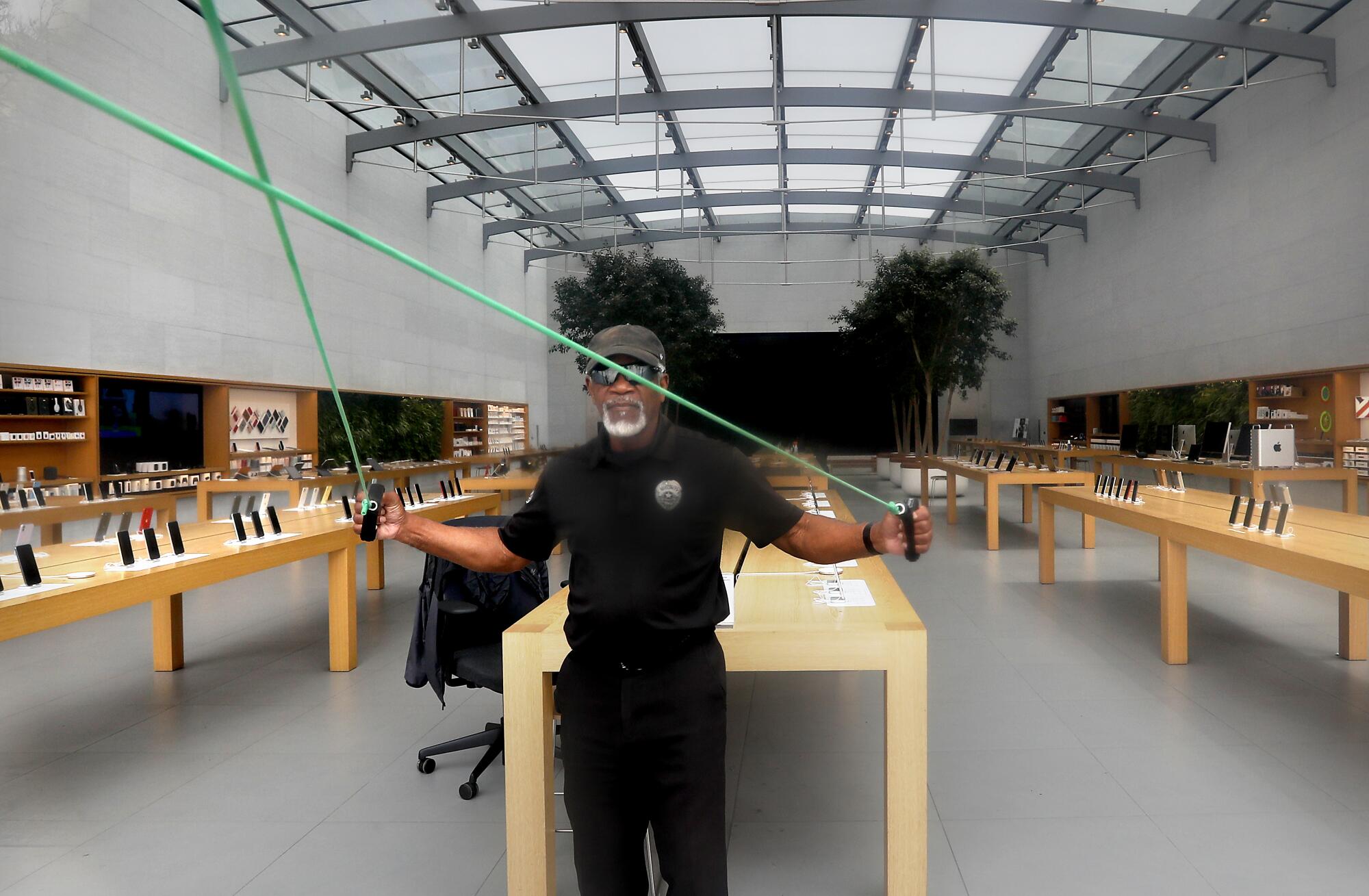 A security guard gets some exercise while keeping watch on the Apple Store at the Third Street Promenade in Santa Monica. As coronavirus restrictions are loosened, retail shops are allowed to reopen if they provide curbside pickup and practice social distancing.