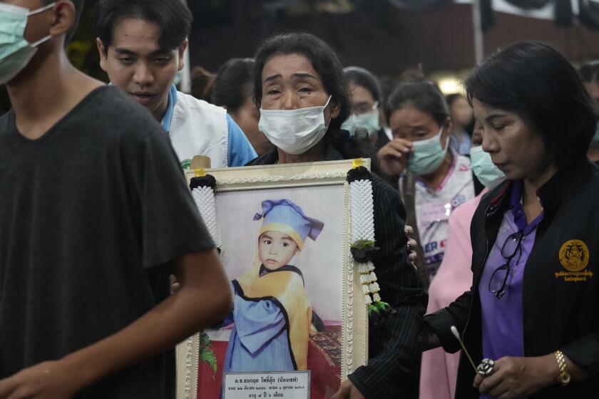 Familiares de las víctimas del incendio de un autobús portan retratos de los fallecidos en una procesión en la escuela Wat Khao Phraya Sangkharam Lan Sak, en la provincia de Uthai Thani, Tailandia, el jueves 3 de octubre de 2024. (Foto AP/Sakchai Lalit)