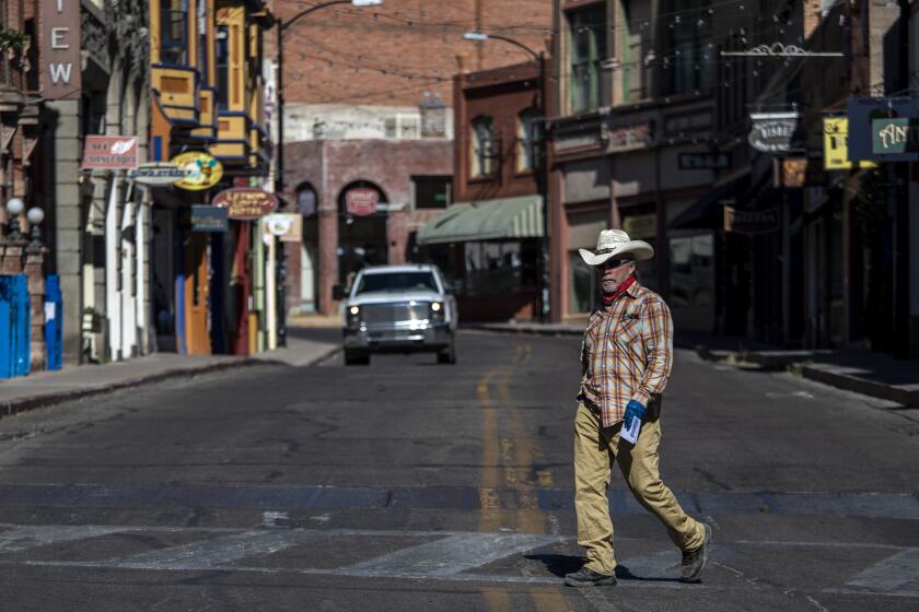 BISBEE, AZ - MAY 26: A man in a hat walks across Main Street Tuesday, May 26, 2020 in Bisbee, AZ. (Brian van der Brug / Los Angeles Times)
