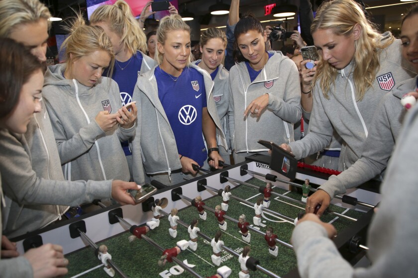 Members of the U.S. women's national soccer team take a look at a table football game with players featuring their likenesses during a media day May 24 in New York.