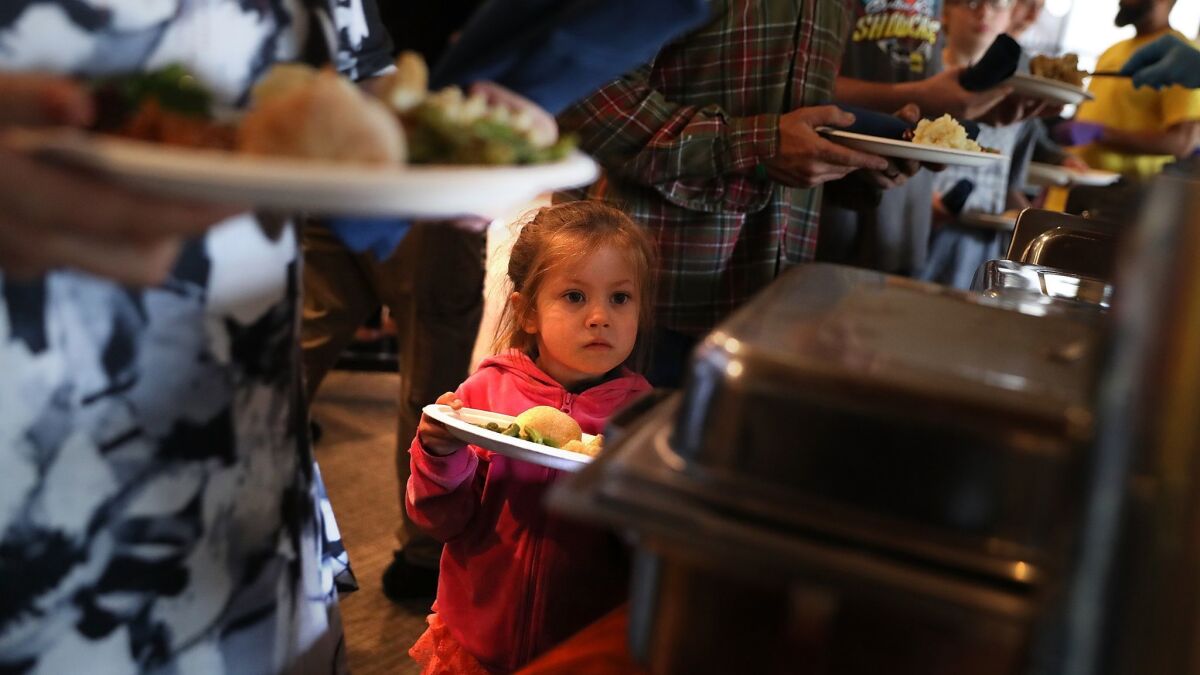 A young Camp fire evacuee waits in line to receive a free Thanksgiving meal Thursday in Chico, Calif.