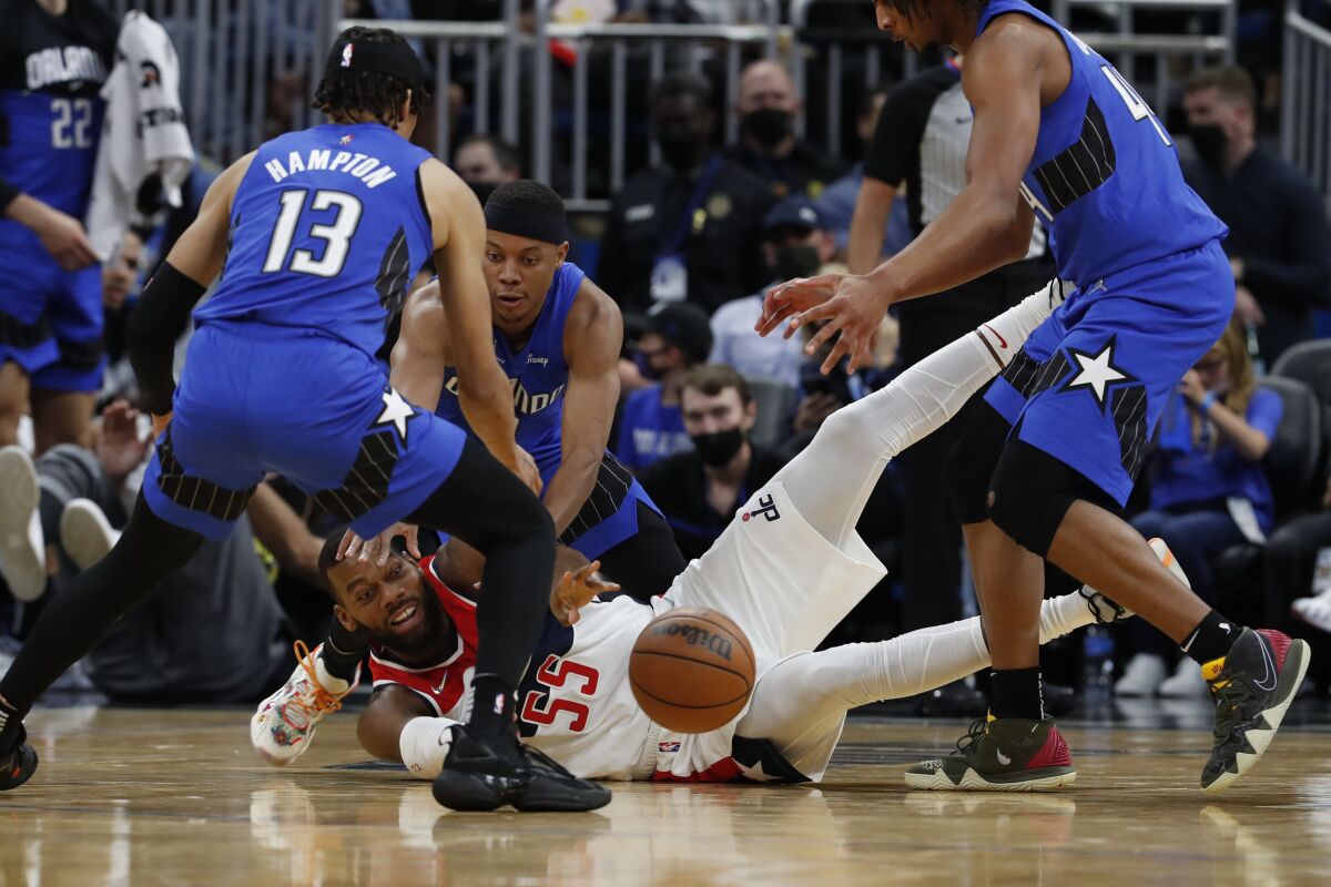 Washington Wizards center Greg Monroe (55) reaches for the ball under pressure, from left to right, Orlando Magic guard R.J. Hampton, guard Tim Frazier and forward Freddie Gillespie during the second half of an NBA basketball game Sunday Jan. 9, 2022, in Orlando, Fla. (AP Photo/Scott Audette)