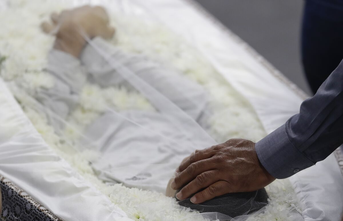 Un familiar coloca su mano en la cabeza de Caio Oliveira, víctima de un tiroteo en una escuela, durante un funeral colectivo para quienes murieron en Suzano, en la zona conurbada de Sao Paulo, Brasil, el jueves 14 de marzo de 2019. (AP Foto/Andre Penner)