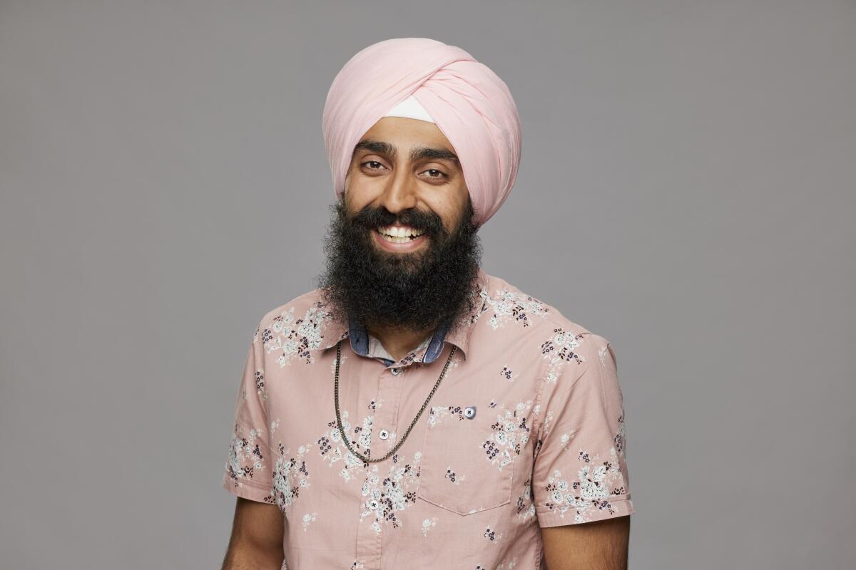Jag Bains smiles while wearing a pink flowered button-up shirt, a matching pink Sikh turban and a necklace
