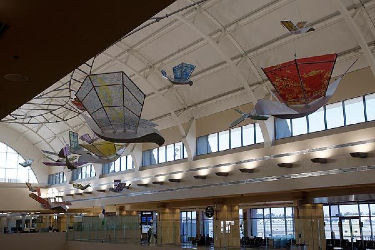 "Flight of Ideas," by artist Beth Nybeck, floats above the baggage carousels in new Terminal C at John Wayne Airport. The sculpture consists of 21 aluminum and plexiglass birds, with wingspans ranging from 3 feet to 14 feet, suspended from an S-shaped structure. The wings display enlargements from aeronautical charts, rendered in multicolored vinyl adhesive. See full story