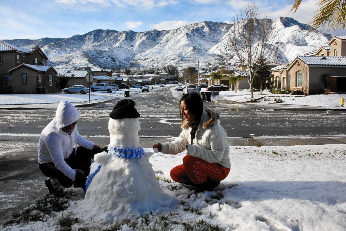 Ariana Zacarias, 16, right, and her mother, Christina Barragan, make a snowman in front of their home after an unusual snowfall in Lake Elsinore on Dec. 31.