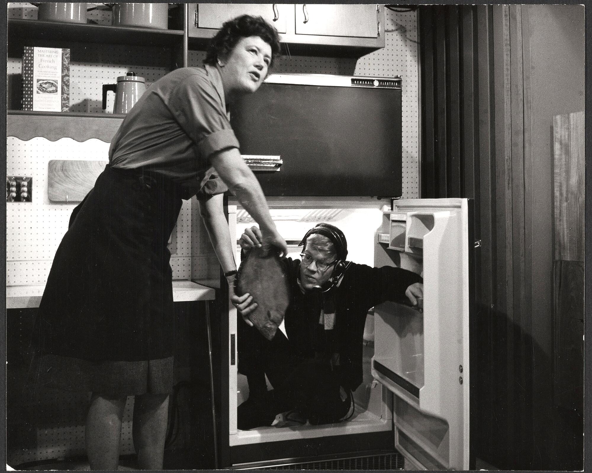 Julia Child retrieving fish from a crew member in a refrigerator, as seen in the documentary "Julia."