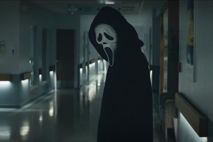 A person in a black cloak and white mask standing in a hallway