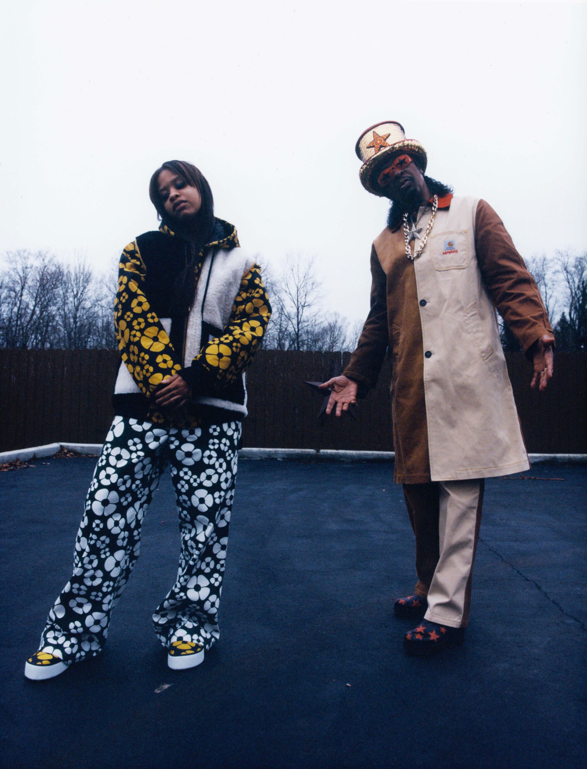 A woman and a man wear boldly patterned and color-blocked pants and jackets.