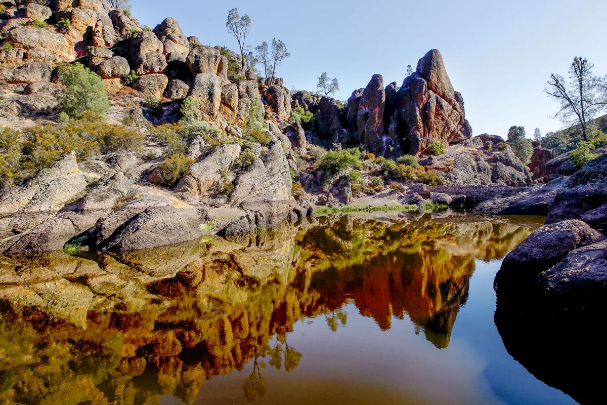 Bear Gulch Reservoir at Pinnacles National Park, with jagged rocks reflecting in calm water.