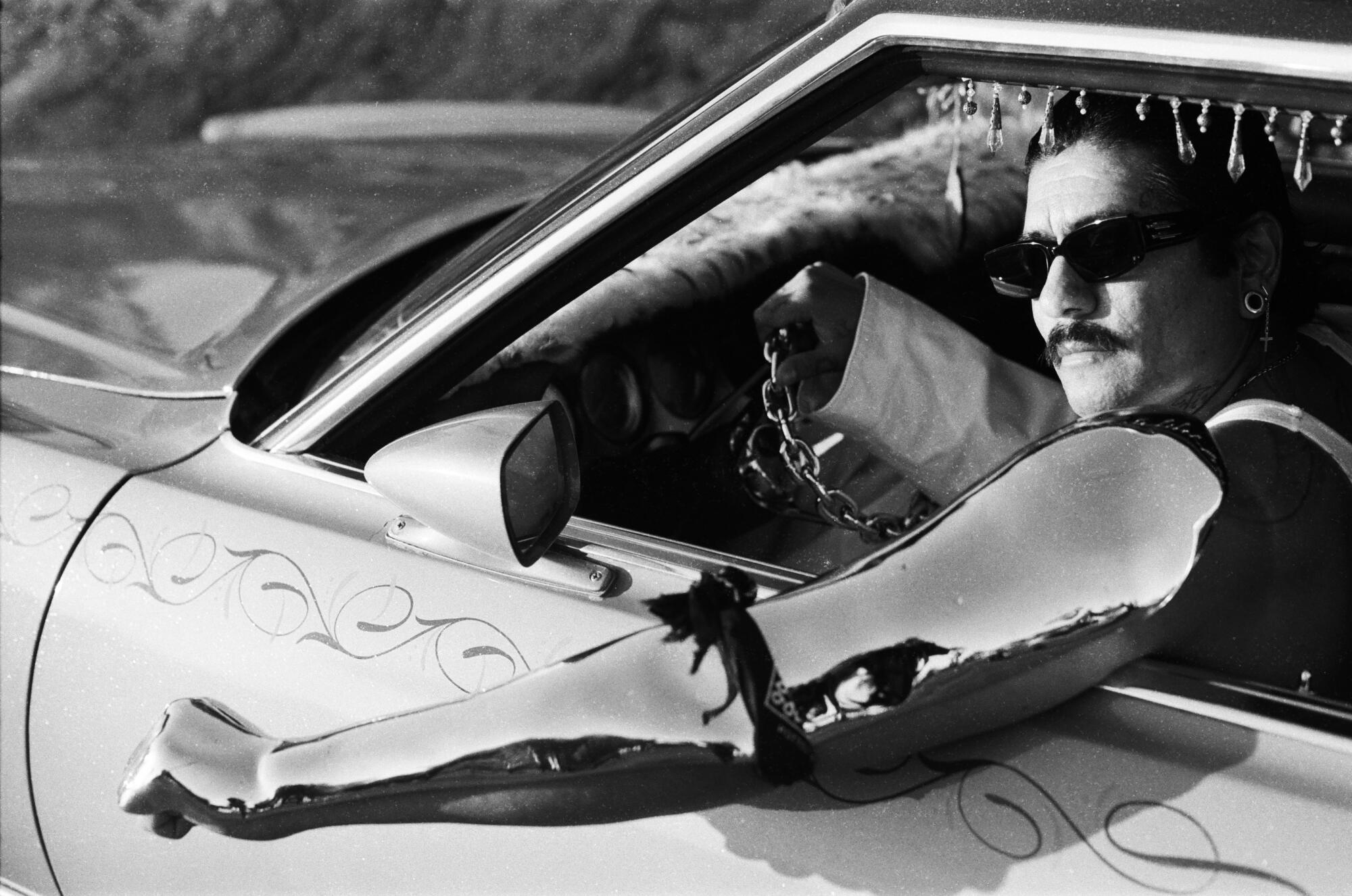 rafa esparza in the lowrider car with chrome-plated arm hanging out window