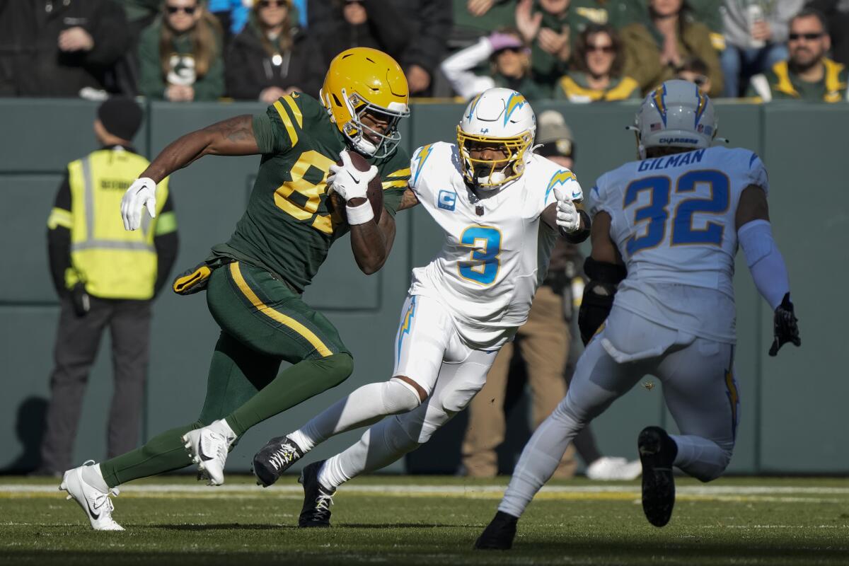 Chargers Derwin James Jr. (3) and Alohi Gilman (32) pursue Green Bay Packers wide receiver Romeo Doubs.