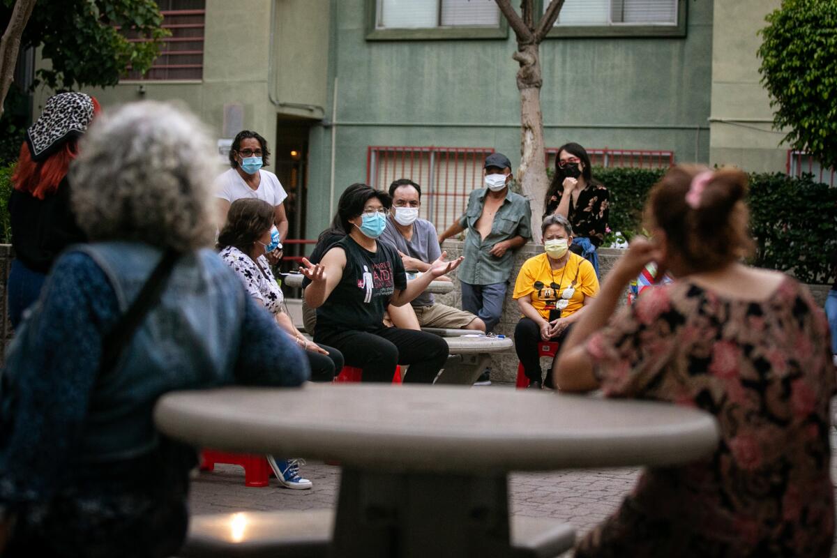 A group of people wearing masks sitting on benches. 