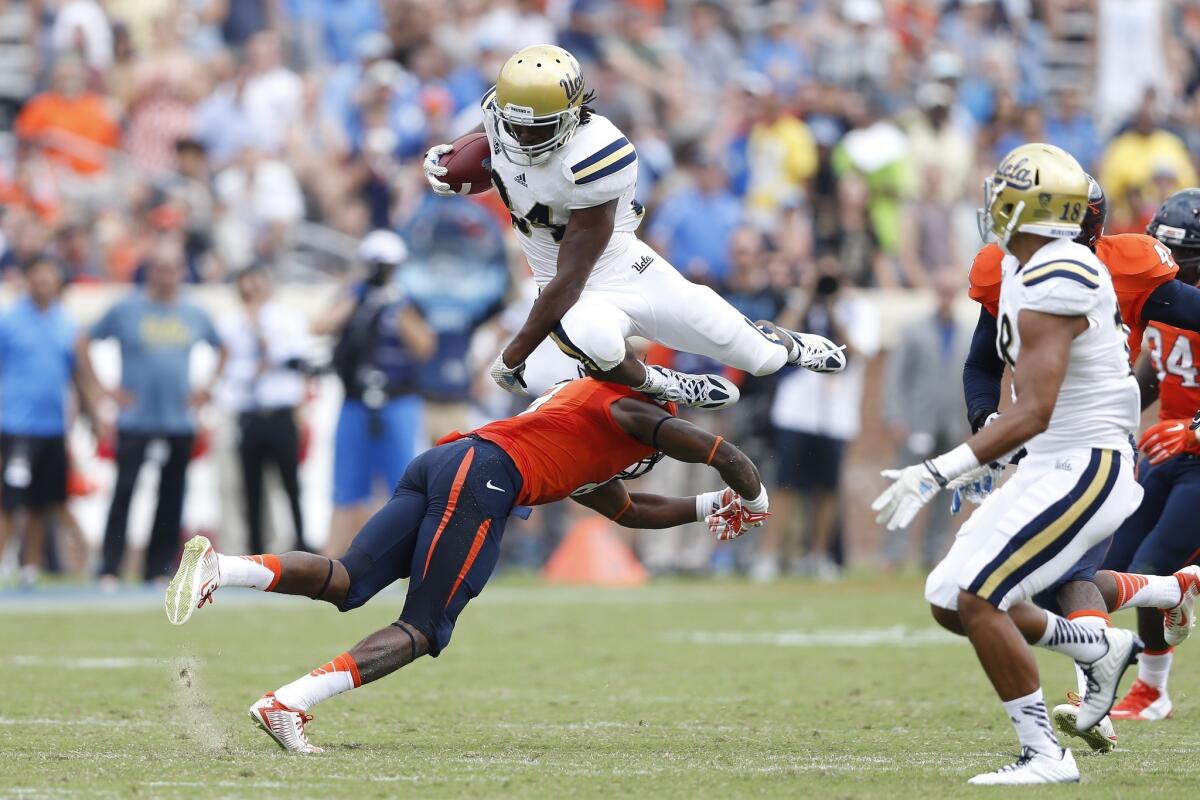 UCLA running back Paul Perkins tries to jump over Virginia's Anthony Harris during the Bruins' 28-20 win over the Cavaliers on Saturday in Charlottesville, Va. at Scott Stadium.