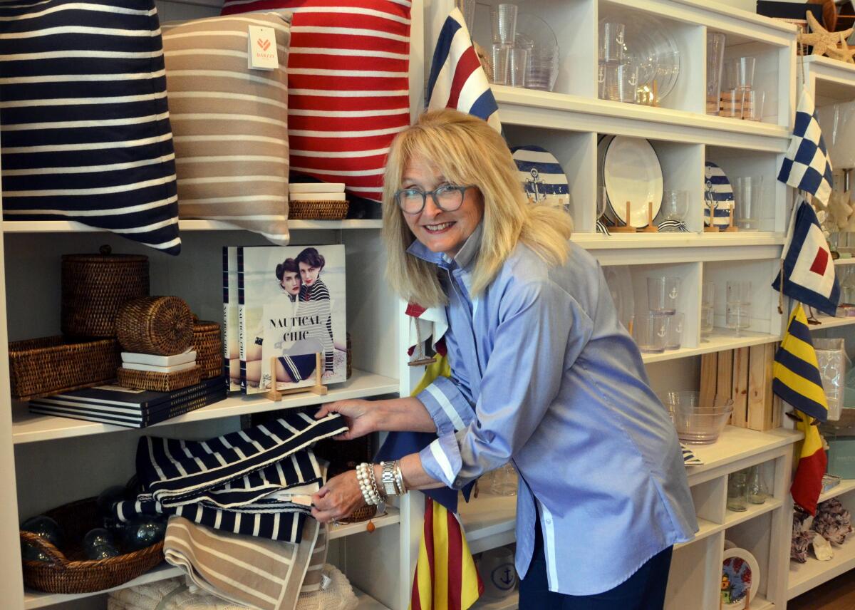 Kathy Hill arranges merchandise on display shelves in Crews Quarters Newport.