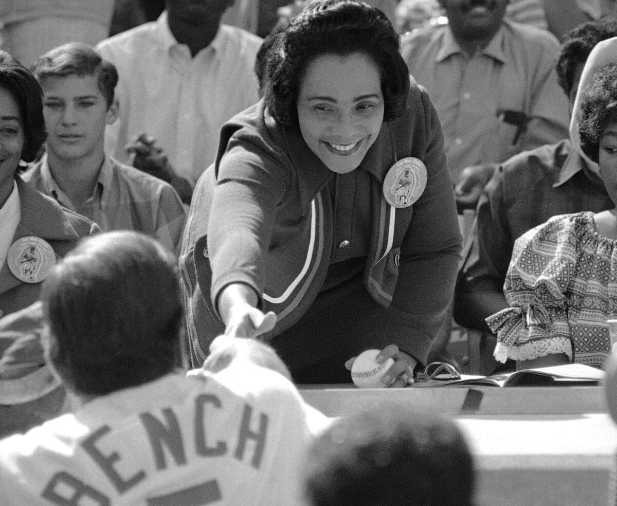 Coretta Scott King, widow of the Rev. Martin Luther King Jr., reaches out to shake hands with catcher Johnny Bench of the Cincinnati Reds, who caught her first pitch thrown at Dodger Stadium in Los Angeles of March 28, 1970, for the East-West All-star game