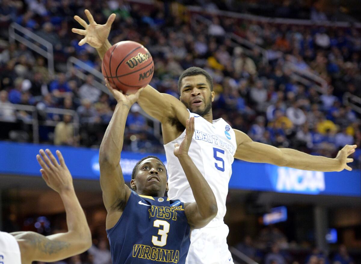 Kentucky guard Andrew Harrison (5) rejects a shot by West Virginia guard Juwan Staten (3) in the second half of a 78-39 victory for the top-ranked Wildcats on Thursday night in an NCAA Midwest Regional game.