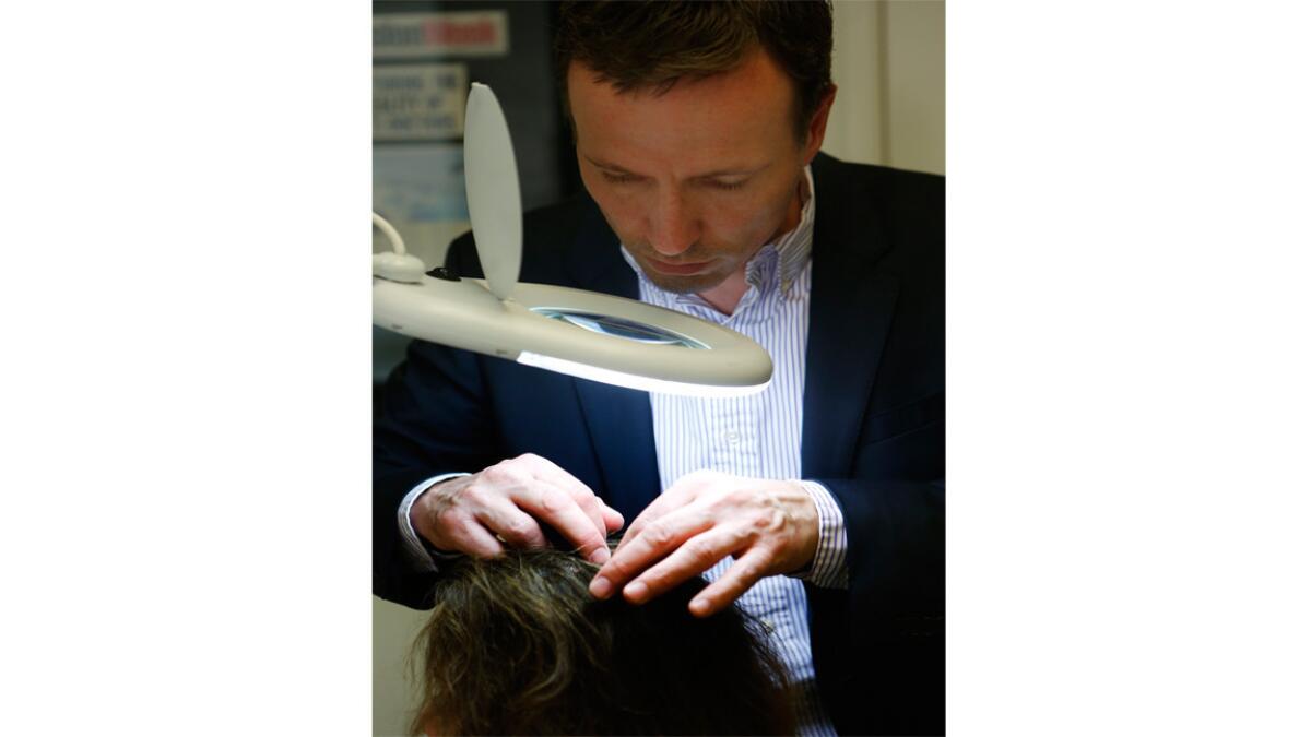 Lars Skjoth, founder and head of research and development for Harklinikken hair regrowth clinics, demonstrates how he examines the scalp of his patients.