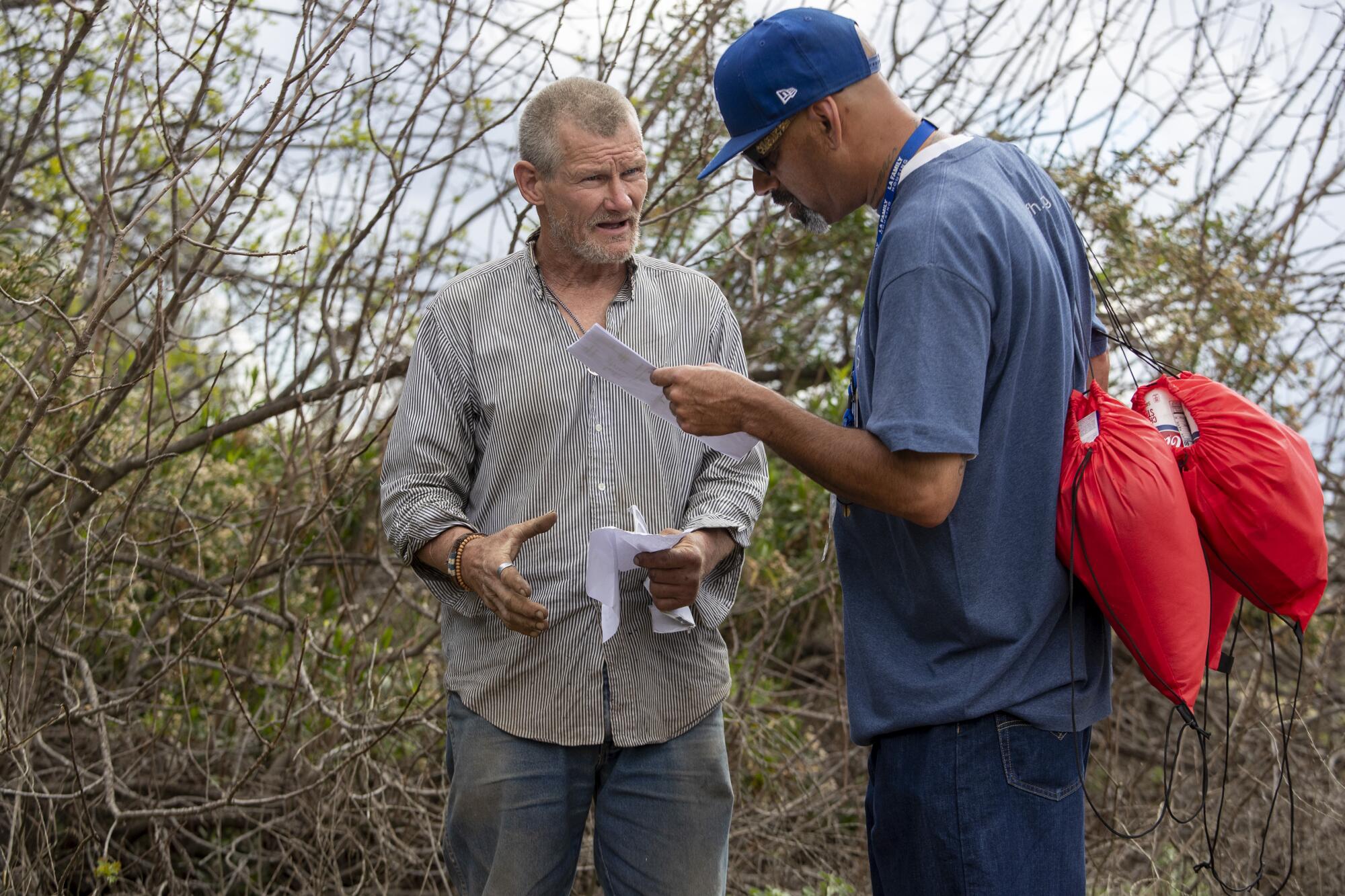 LA Family Housing outreach coordinator Eric Montoya, right, interviews homeless man Patrick Moran, who is camped in the Sepulveda Basin in Encino.