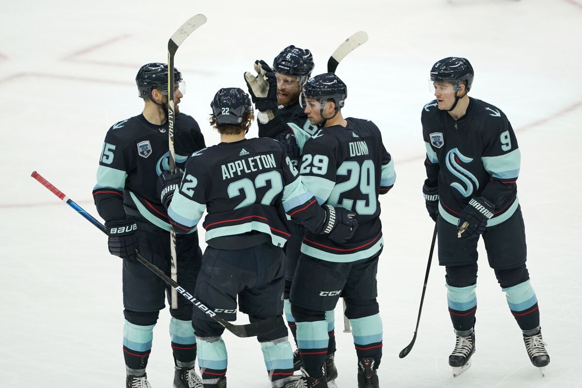 Seattle Kraken defenseman Vince Dunn (29) is greeted by teammates after he scored a goal against the Chicago Blackhawks during the second period of an NHL hockey game, Monday, Jan. 17, 2022, in Seattle. (AP Photo/Ted S. Warren)