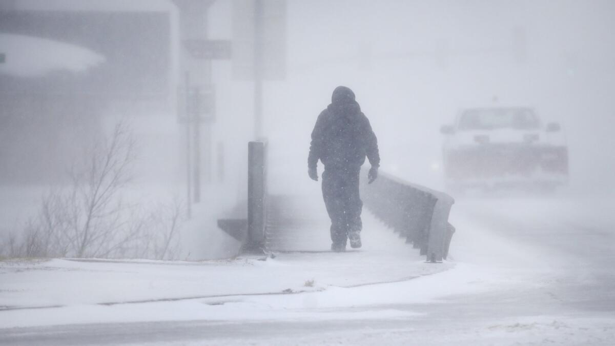 A man crosses Crow Creek during a blizzard on Wednesday in Cheyenne, Wyo.