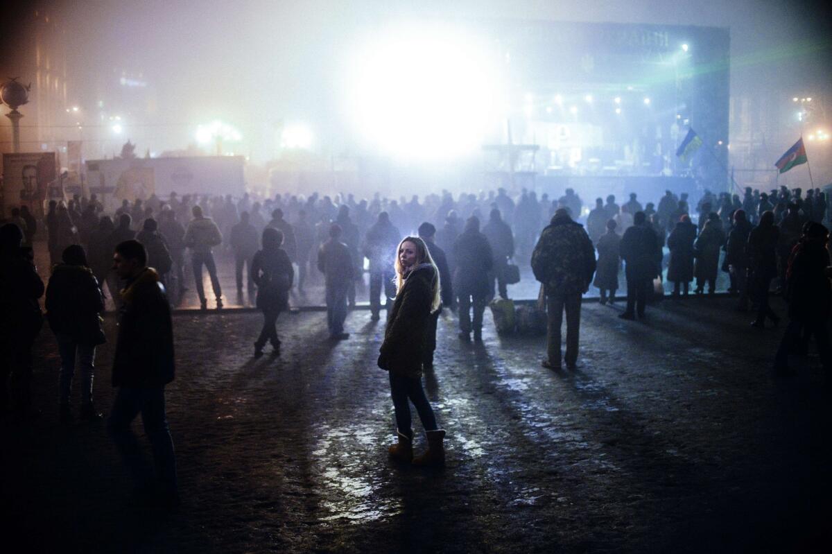 A woman looks on as people watch news on a large TV screen at Independence Square in central Kiev. Russian forces have surrounded Ukrainian military bases across Crimea as the Russian-speaking autonomous region has been thrown into turmoil following the ouster last month of Moscow-backed president Viktor Yanukovych.