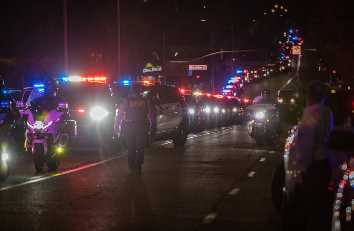 Law enforcement line up their vehicles to form a procession.
