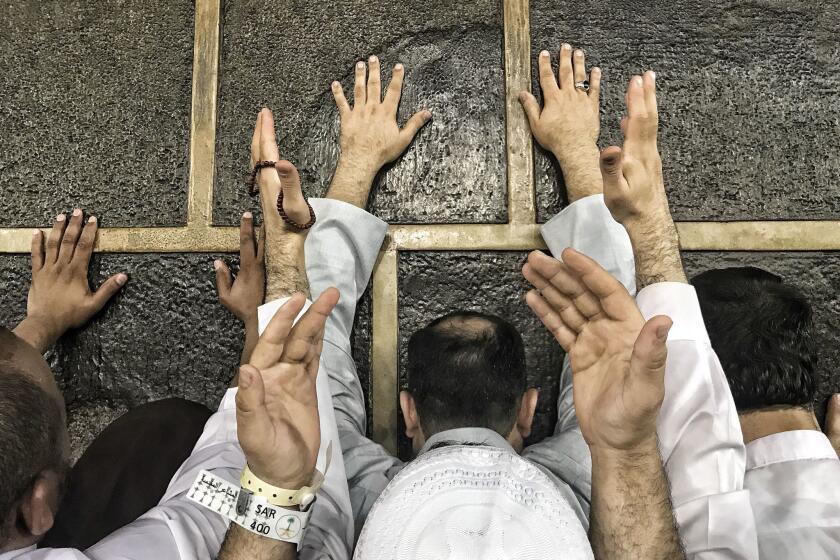 Hajj pilgrims touch the wall of the Kaaba, Islam's holiest site, in the Saudi Arabian city of Mecca on Saturday. About 2 1/2 million Muslims are expected to take part in the pilgrimage to Mecca this year.