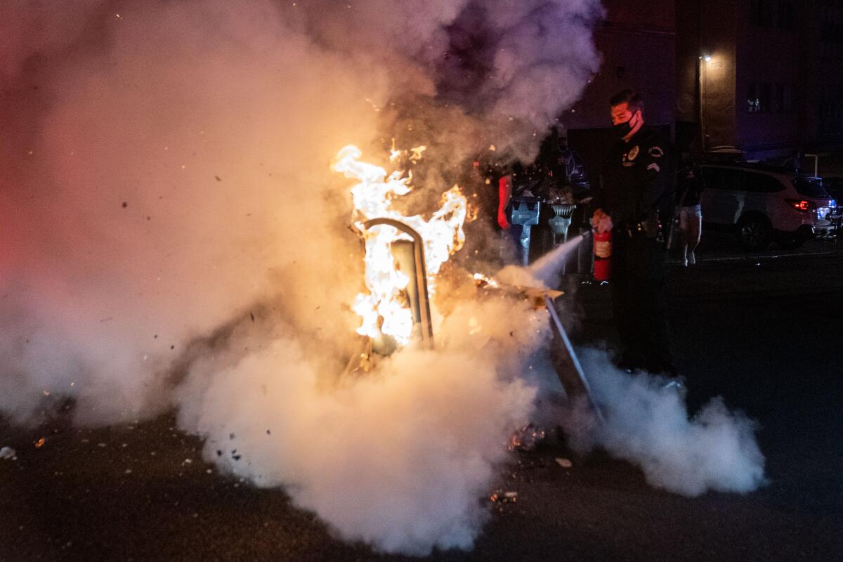 A police officer uses a fire extinguisher on a small blaze in Westwood in April 2021. 