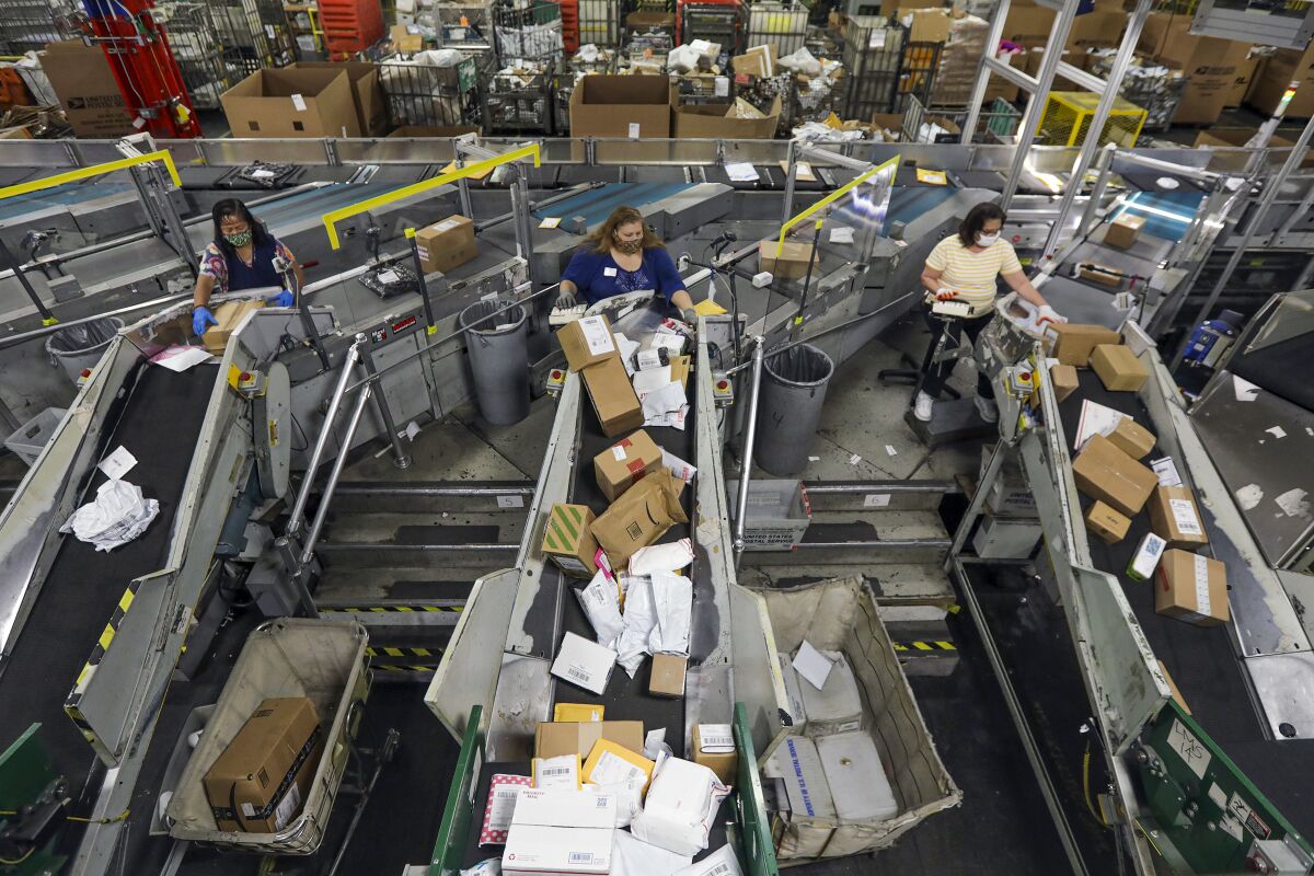 Employees work with an automated parcel and bundle sorter at the Postal Service center in the City of Industry.