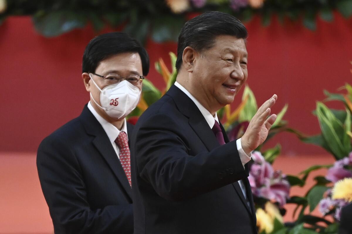 China's Xi Jinping waves, accompanied by Hong Kong's John Lee. 