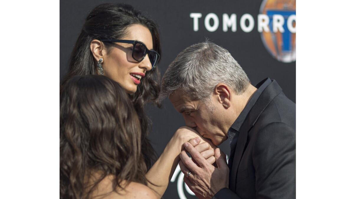 George Clooney kisses wife Amal Clooney on the hand at the "Tomorrowland" premiere, because <i>of course</1> he's the type of guy who would kiss his wife on the hand.