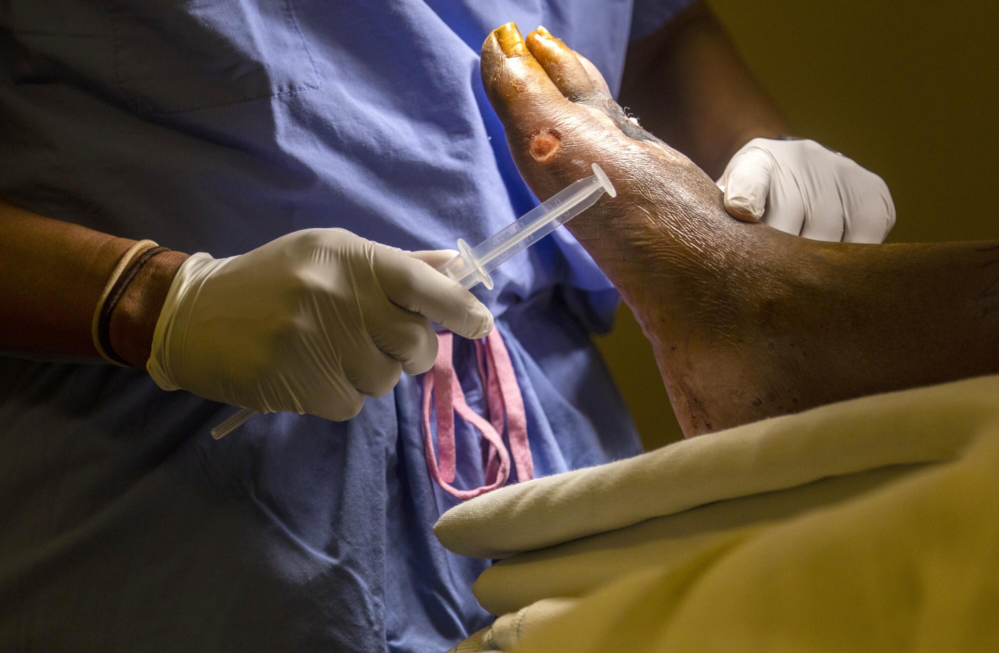 Dr. Myron Hall, left, checks for a pulse on Glory Paschal's foot before operating.