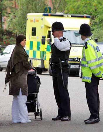 Officers question a woman during a police operation last month in London. A British Muslim leader has urged Muslim women not to wear their head scarves, fearing for their safety.
