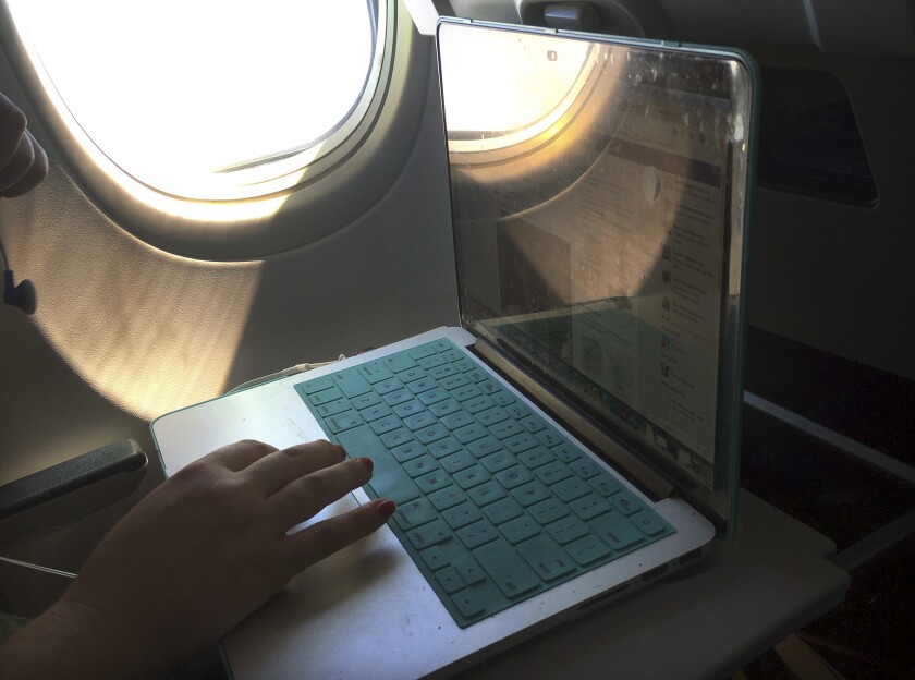 FILE - A passenger uses a laptop aboard a commercial airline flight from Boston to Atlanta on July 1, 2017. Concern about new high-speed wireless service interfering with airplanes appears to be easing. Federal safety regulators said Friday, Jan. 28, 2022 they have cleared the way for Verizon and AT&T to turn on more 5G towers. (AP Photo/Bill Sikes, File)